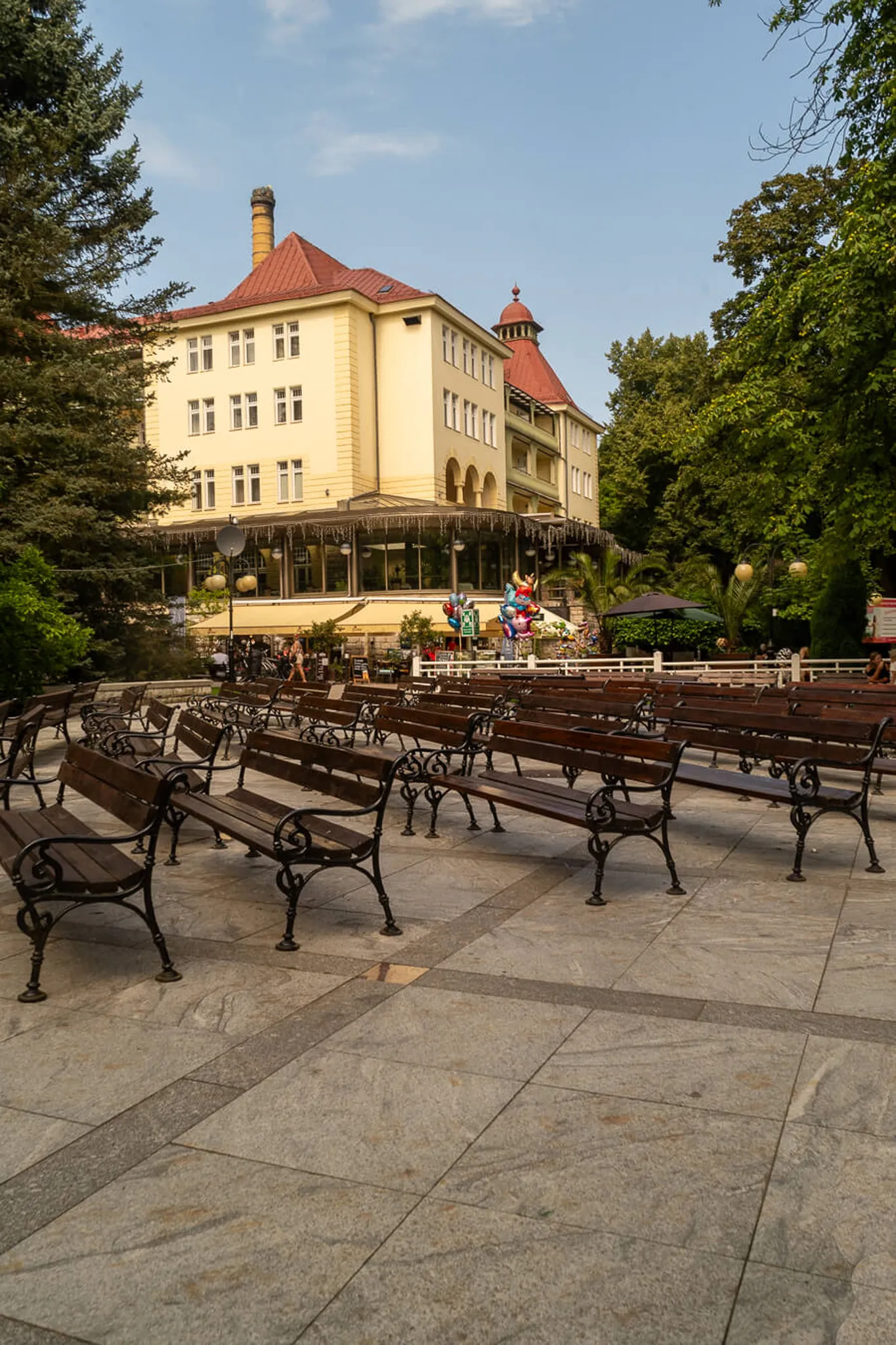 Klimatyczny wieczorny deptak w Polanicy Zdrój — zabytkowe latarnie wieża kościoła NMP w tle kawiarnie i turyści o zmierzchu