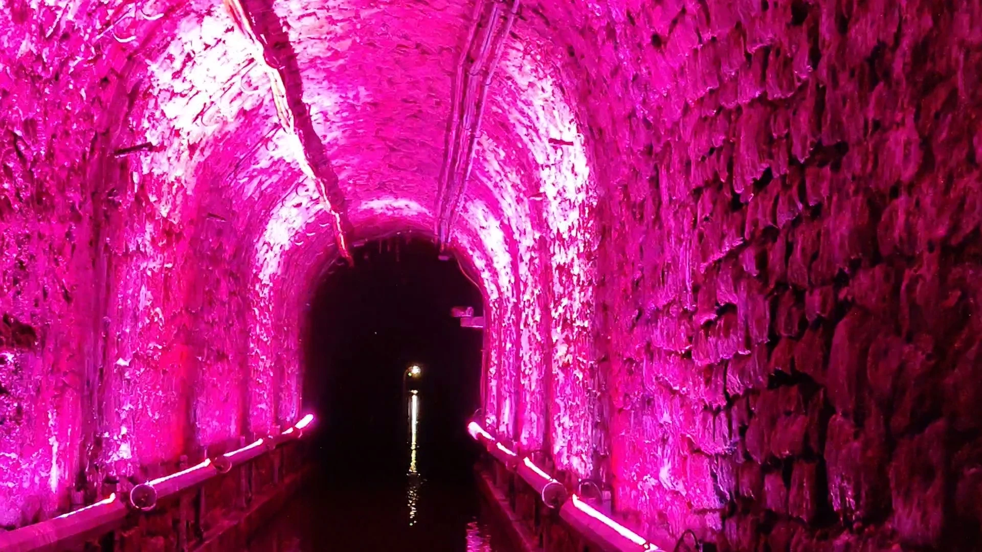 Kolorowa iluminacja tunelu podczas spływu w Sztolni Luiza Zabrze Podziemny tunel z różową iluminacją podczas spływu łodzią w Sztolni Królowa Luiza w Zabrzu